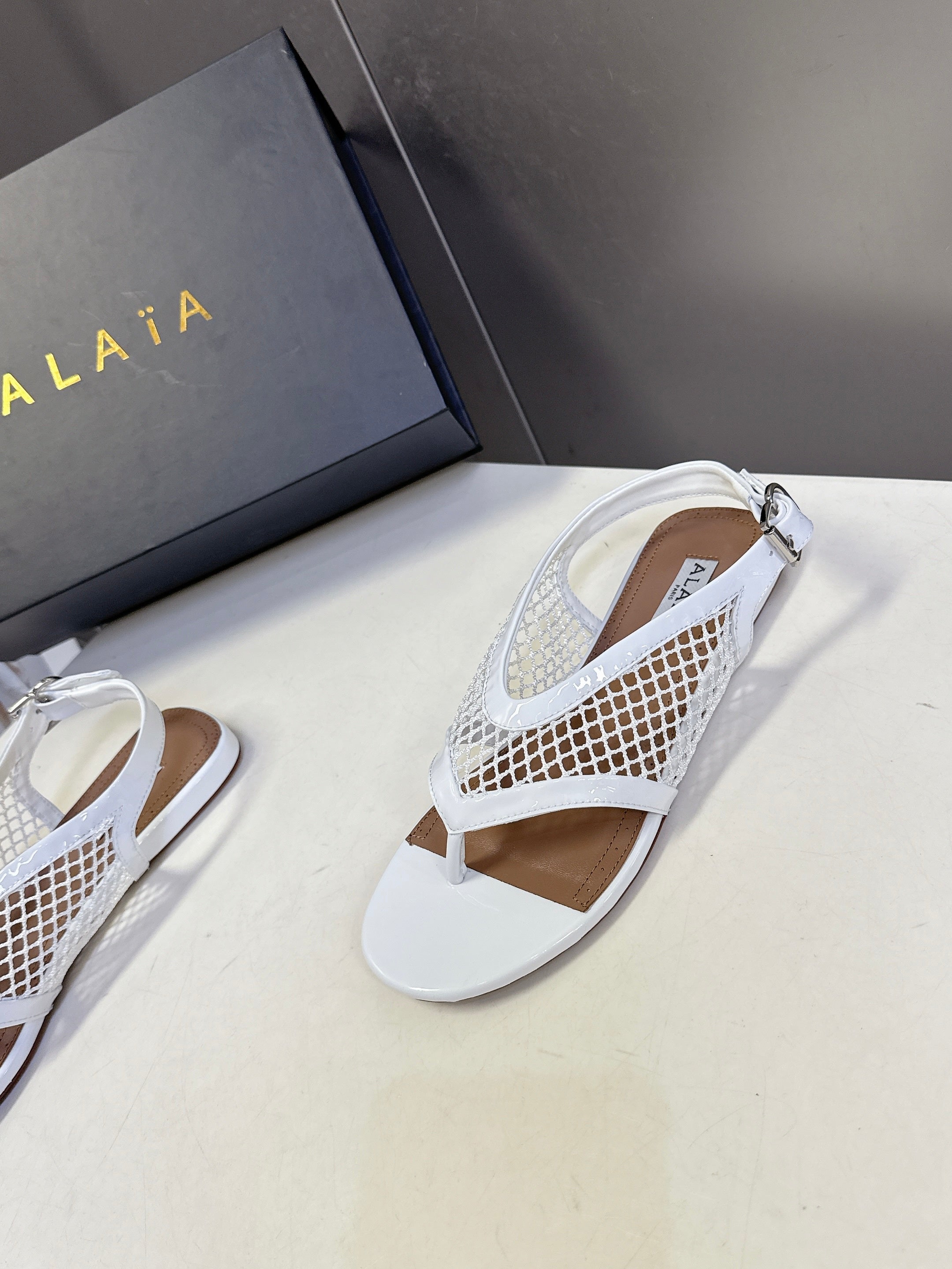 ALAIA 26S FLAT MESH THONG SANDALS IN WHITE PATENT CALFSKIN