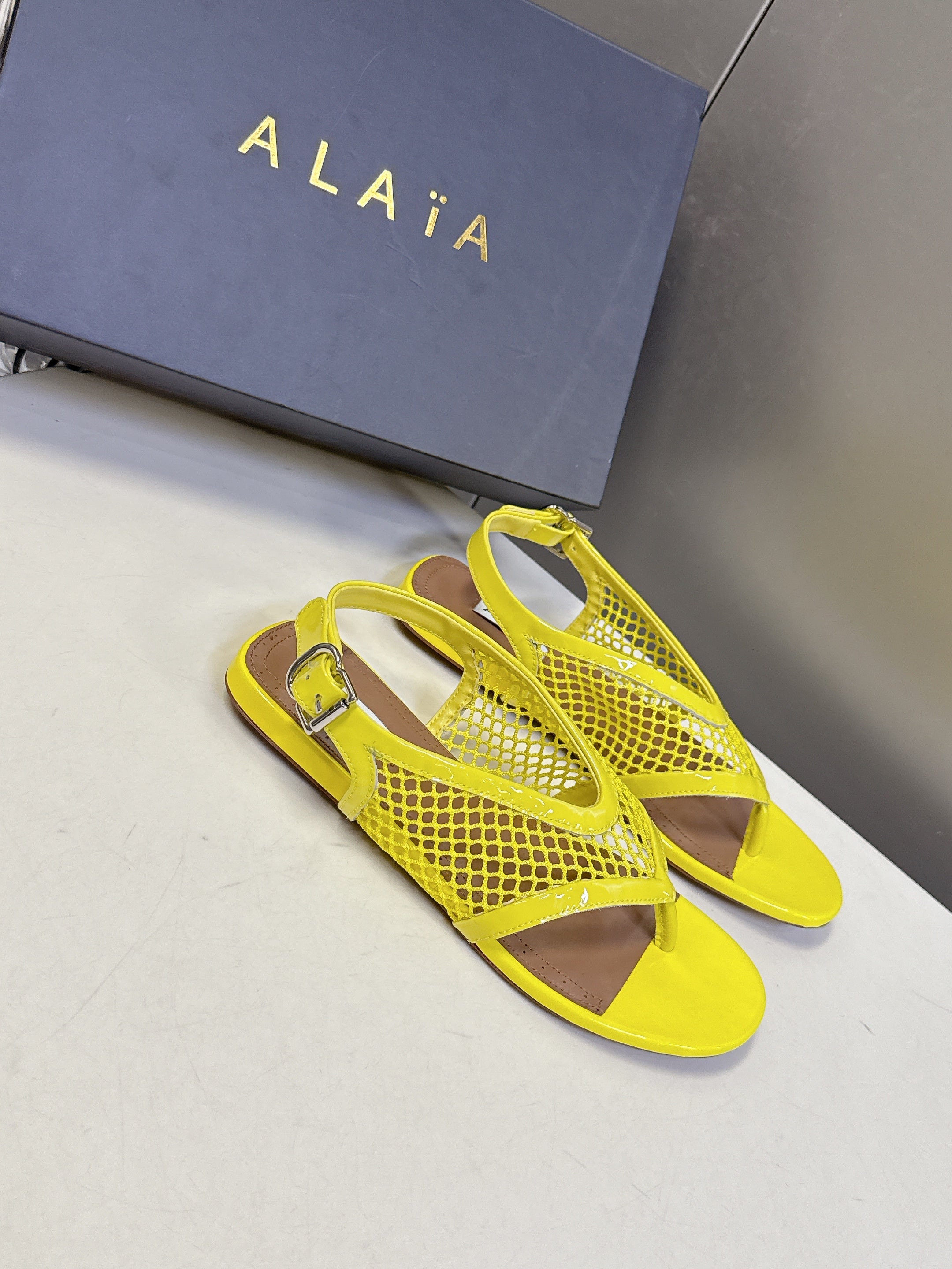 ALAIA 26S FLAT MESH THONG SANDALS IN YELLOW PATENT CALFSKIN